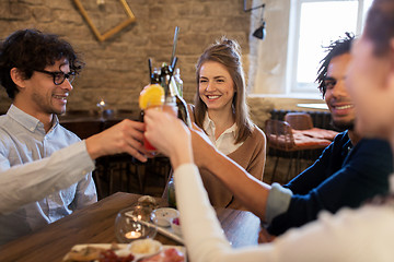 Image showing happy friends clinking drinks at bar or cafe