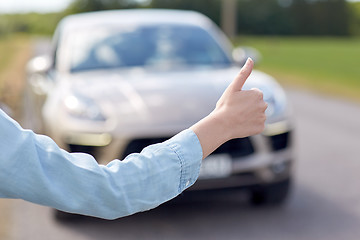 Image showing woman hitchhiking and stopping car with thumbs up