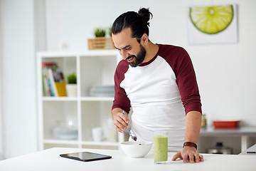 Image showing man with tablet pc eating breakfast at home