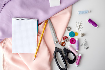 Image showing scissors, sewing tools, cloth and notepad