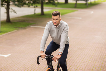 Image showing young man riding bicycle on city street