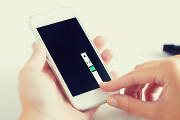 Image showing close up of woman with smartphone doing blood test