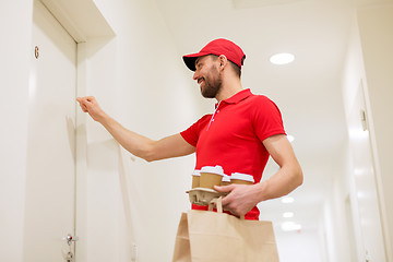 Image showing delivery man with coffee and food knocking on door