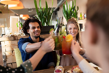 Image showing happy friends clinking drinks at restaurant