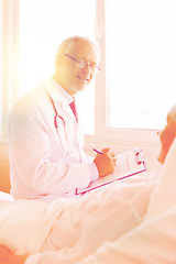 Image showing senior woman and doctor with clipboard at hospital