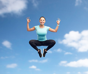 Image showing happy smiling sporty young woman jumping in air