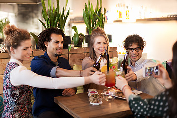 Image showing happy friends clinking drinks at bar or cafe