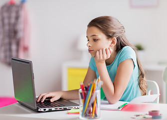 Image showing bored girl with laptop and notebook at home