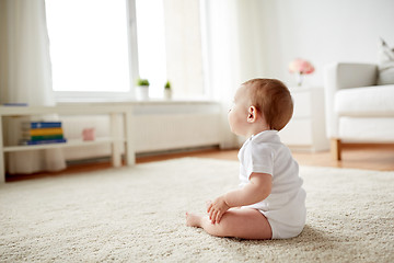 Image showing happy baby boy or girl sitting on floor at home