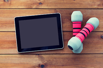 Image showing close up of dumbbells and tablet pc on wood