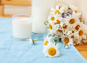 Image showing Simply stylish wooden kitchen with bottle of milk and glass on table, summer flowers camomile, healthy foog moring concept noone 