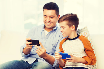 Image showing happy father and son with smartphones at home