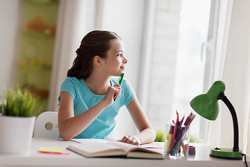 Image showing happy girl with book writing to notebook at home