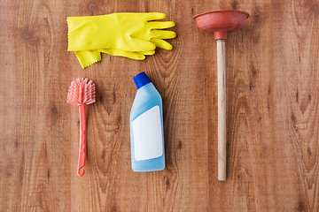 Image showing plunger with cleaning stuff on wooden background