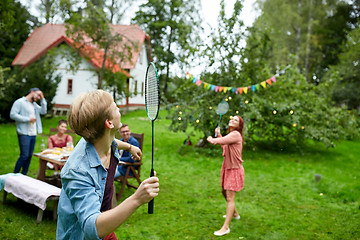 Image showing happy friends playing badminton at summer garden