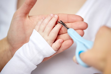 Image showing close up of hand with scissors trimming baby nails