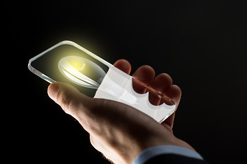 Image showing close up of hand with lightbulb on smartphone