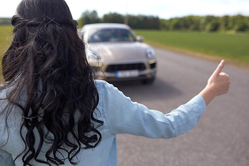 Image showing woman hitchhiking and stopping car with thumbs up