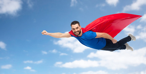 Image showing happy man in red superhero cape flying over sky