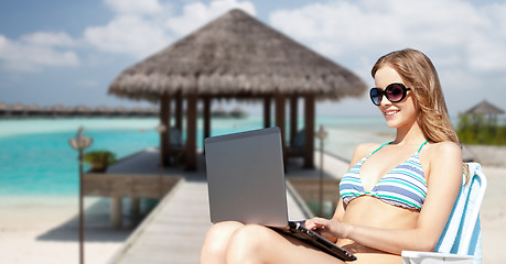 Image showing happy young woman in shades with laptop on beach