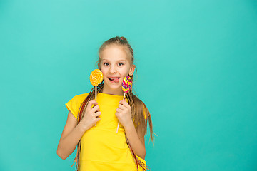 Image showing The teen girl with colorful lollipop on a blue background