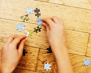 Image showing little kid playing with puzzles on wooden floor together with parent, lifestyle people concept, loving hands to each other 