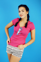 Image showing young pretty teenage modern hipster girl posing emotional happy smiling on blue background, lifestyle people concept 