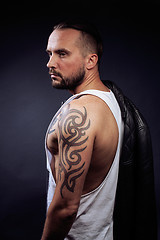 Image showing A man with tattooes on his arms. Silhouette of muscular body. caucasian brutal hipster guy with modern haircut, looking like criminal