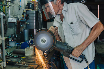 Image showing Senior man working with angle grinder