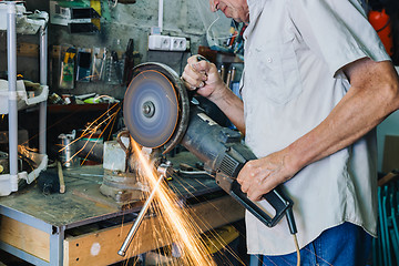 Image showing Senior man working with angle grinder