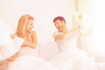 Image showing happy couple having pillow fight in bed at home