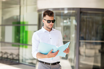 Image showing young man with business file on city street