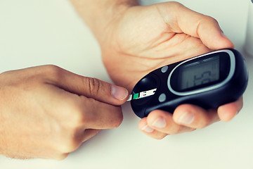 Image showing close up of man checking blood sugar by glucometer