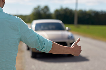 Image showing man hitchhiking and stopping car with thumbs up