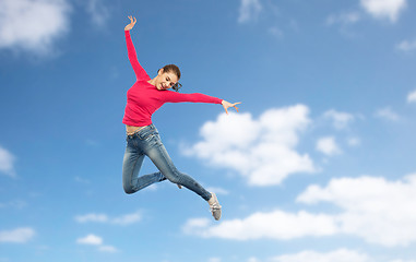 Image showing happy young woman jumping in air or dancing