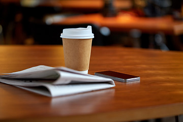 Image showing coffee cup, smartphone and newspaper on cafe table