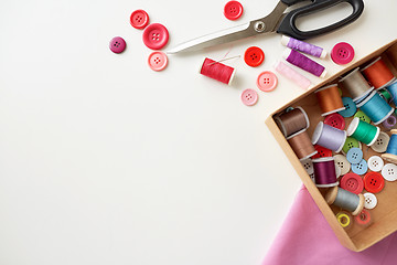 Image showing box with thread spools and sewing buttons on table