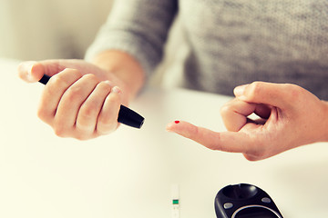 Image showing close up of woman making blood test by glucometer