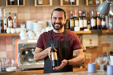 Image showing happy man or waiter with bottle of red wine at bar