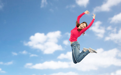 Image showing happy young woman jumping in air or dancing