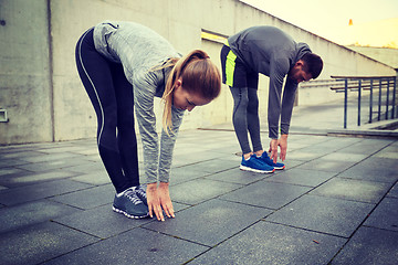Image showing couple stretching and bending forward on street
