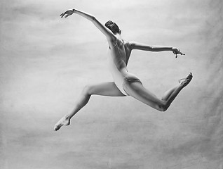 Image showing Young beautiful modern style dancer jumping on a studio background