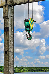 Image showing Yellow-green hook of a construction crane on a rope on a background of clouds