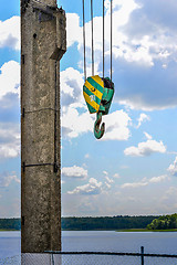 Image showing Yellow-green hook of a construction crane on a rope on a background of clouds