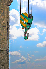 Image showing Yellow-green hook of a construction crane on a rope on a background of clouds