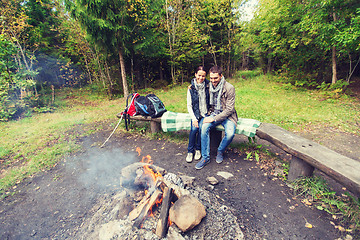 Image showing happy couple sitting on bench near camp fire