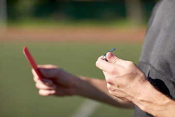 Image showing referee hands with red card on football field