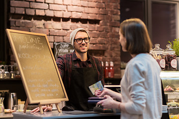Image showing happy barman and woman paying money at cafe