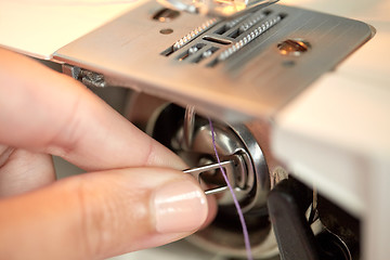 Image showing tailor hand setting spool to sewing machine