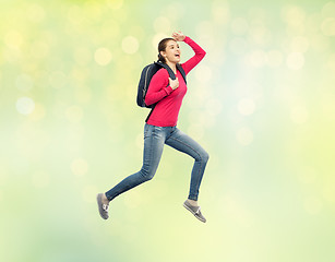 Image showing happy woman or student with backpack jumping